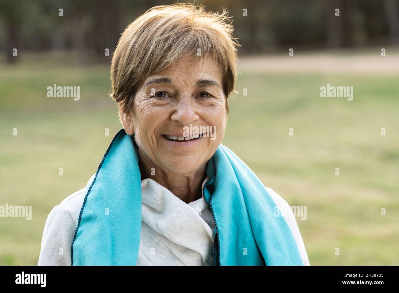 Portrait d'une femme âgée souriant à l'appareil photo après une séance de sport d'entraînement en plein air au parc de la ville - Focus sur le visage Banque D'Images