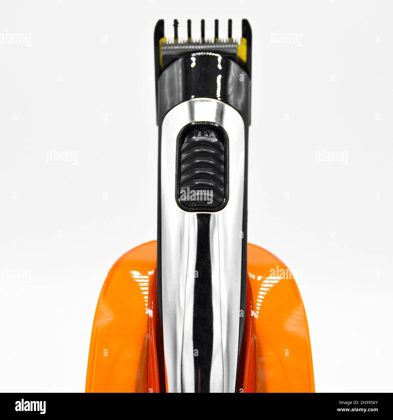 Rasoir électrique sans fil et chromé et chargeur orange, tondeuse cheveux chargée isolée sur fond blanc Banque D'Images
