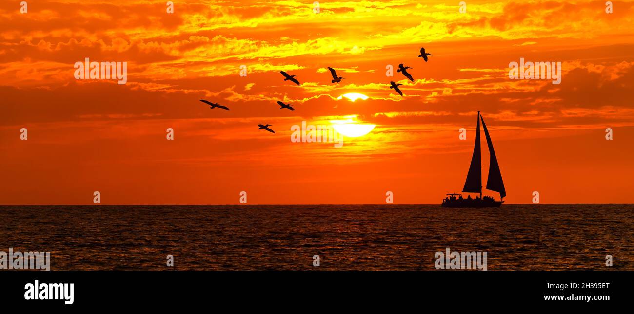Un Voilier navigue le long de l'océan avec Un coucher de soleil coloré dans le format d'image de style bannière Banque D'Images