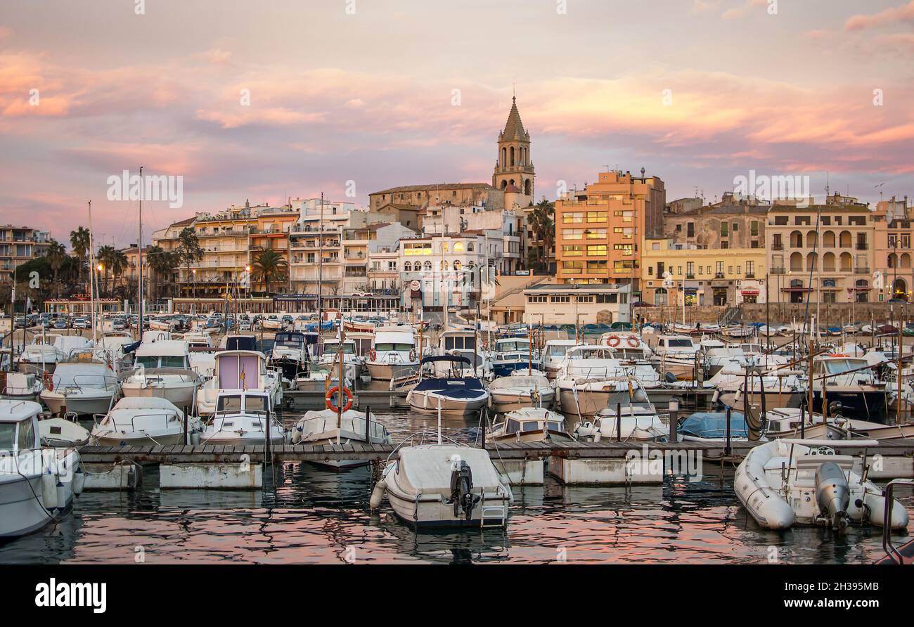 Coucher de soleil avec le ciel doré de la ville de Palamós à Gérone, Costa Brava, avec son clocher caractéristique et les bateaux amarrés dans le port Banque D'Images