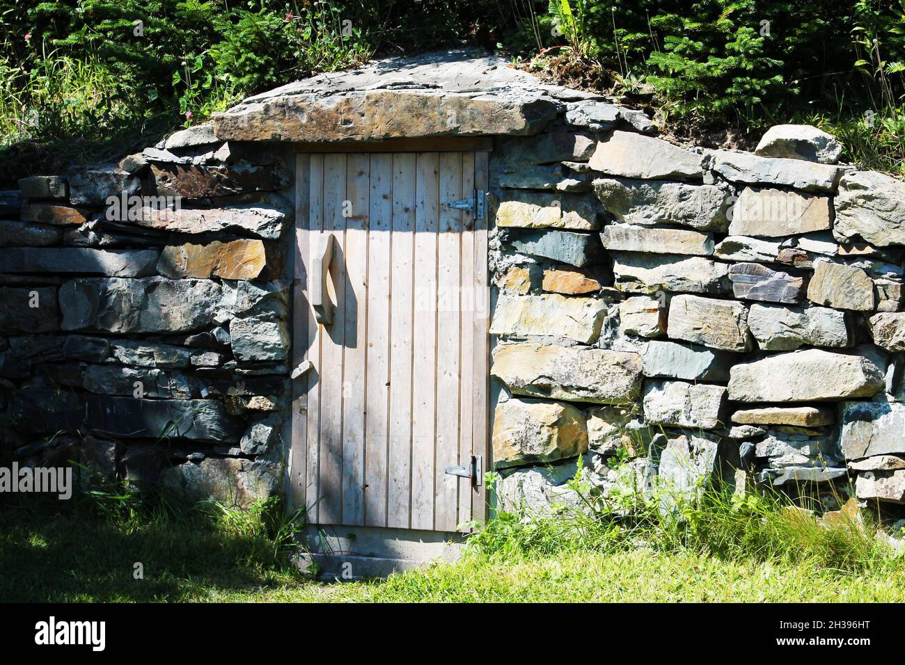 Une ancienne cave à racines avec une façade en pierre et une porte en bois, Elliston, NL. Banque D'Images