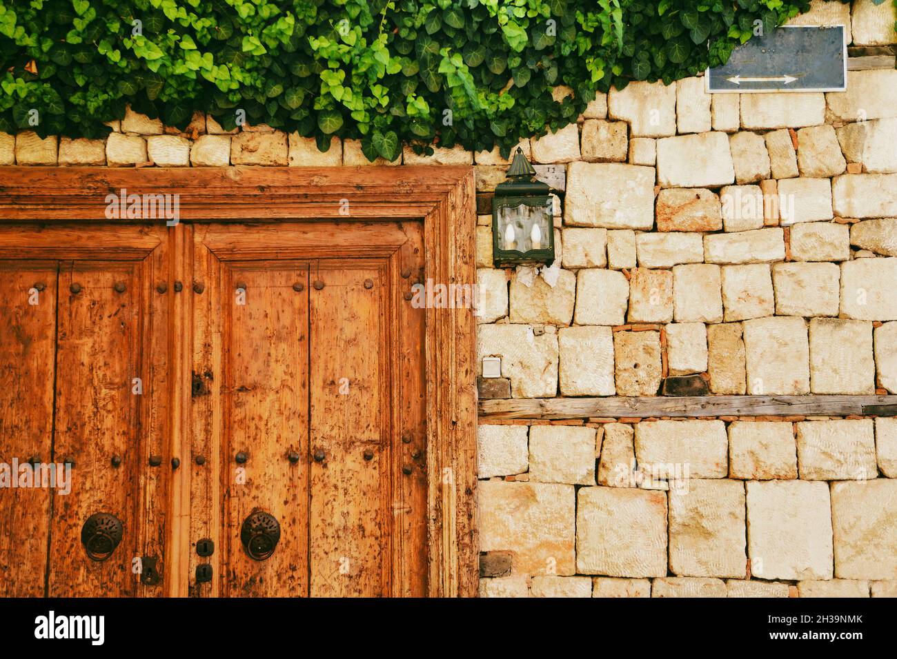 vue de face sur l'ancienne porte en bois, mur de briques et lierre verte recouvrant le mur Banque D'Images