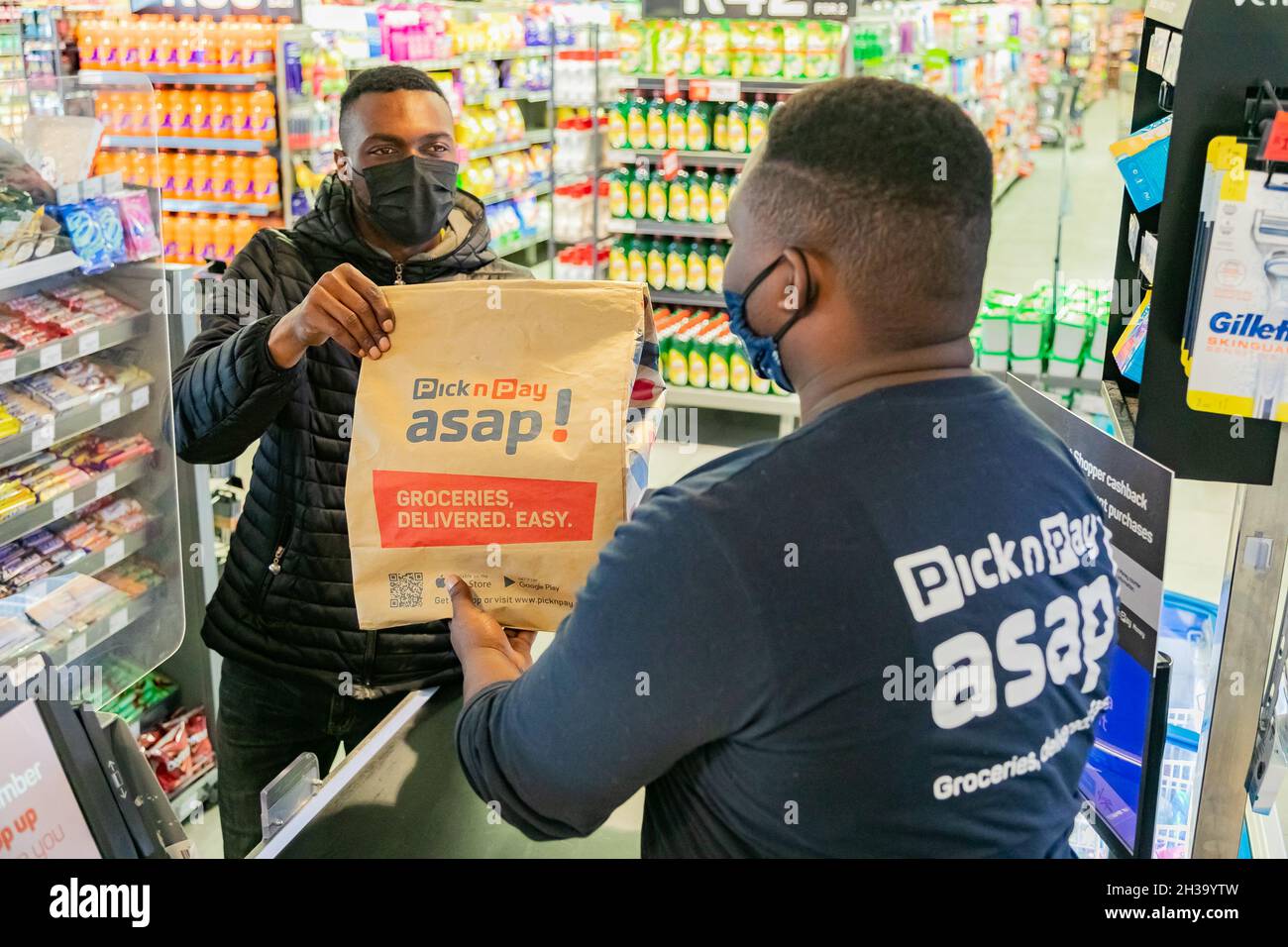 Cape Town, Afrique du Sud - 9 septembre 2021 : le livreur Express Service collecte la commande auprès du personnel au comptoir à l'intérieur de l'épicerie locale Pick n Pay Banque D'Images