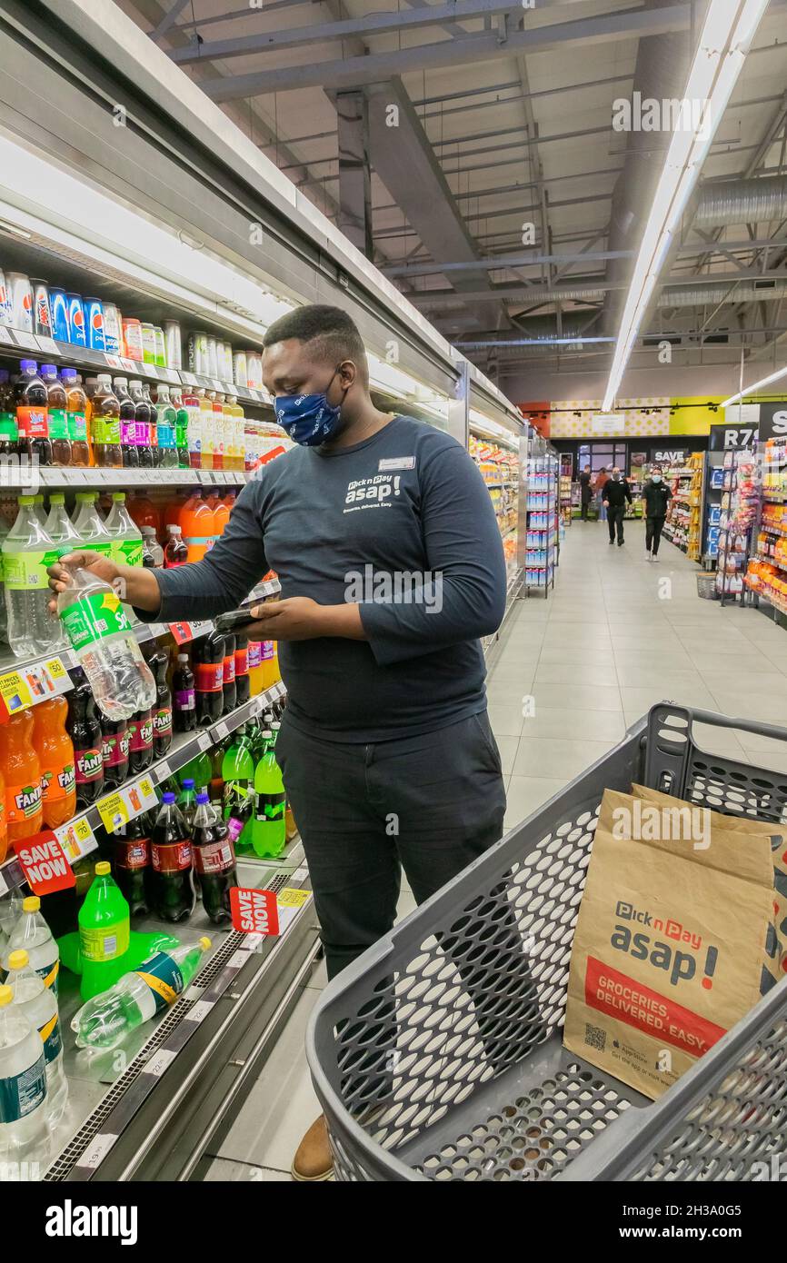 Cape Town, Afrique du Sud - 9 septembre 2021 : un membre du personnel cueille des produits à partir de l'étagère pour un service de livraison express à domicile Banque D'Images