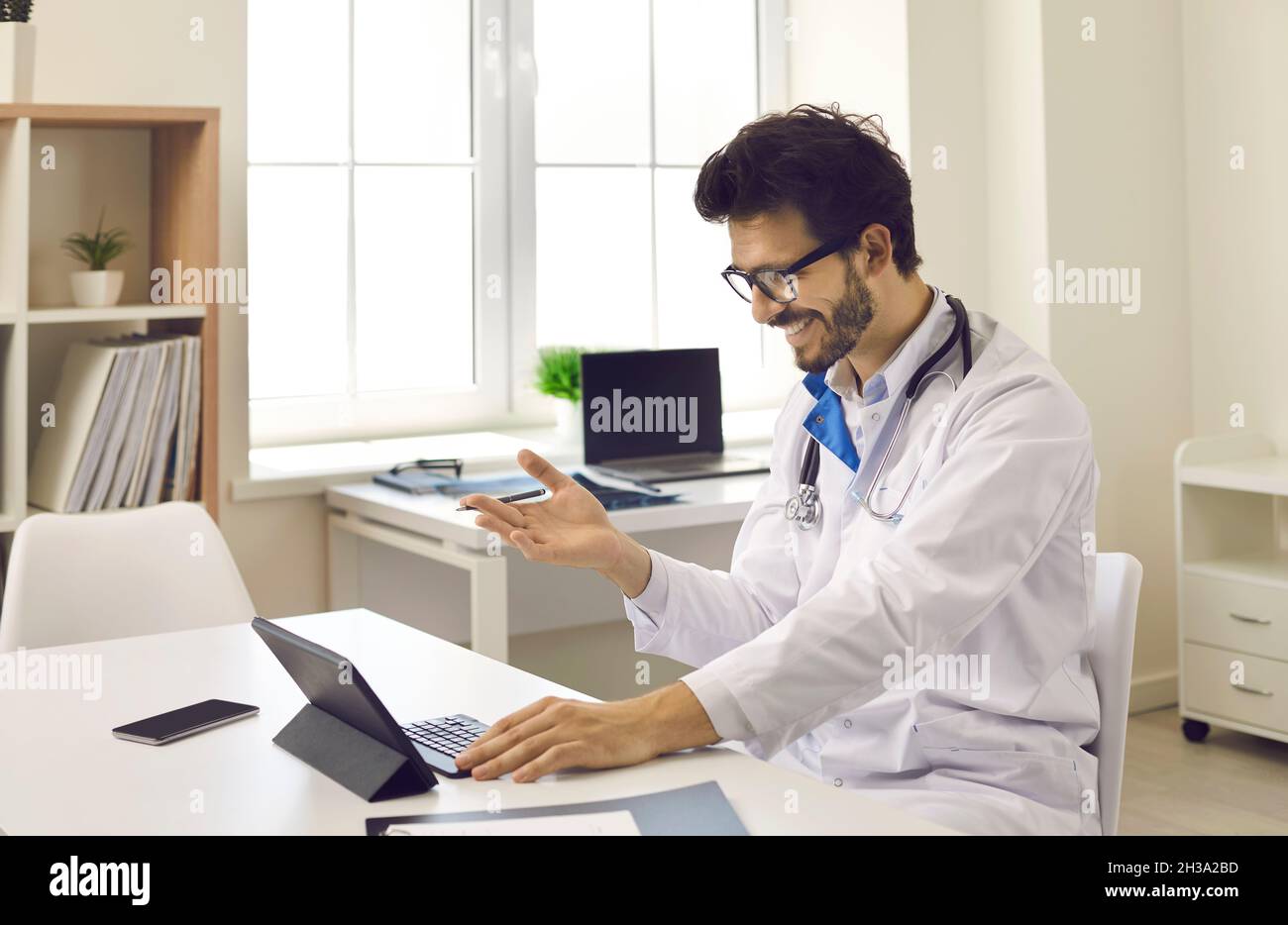 Un médecin en ligne heureux avec une tablette est en appel vidéo avec son patient Banque D'Images