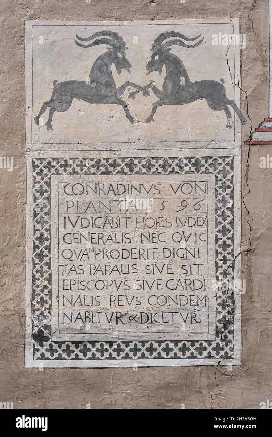 Deux mâles ibexes alpins ou chèvres de montagne paw l'air dans une confrontation au-dessus d'une inscription sgraffito latin datée de 1596 sur la façade d'une maison familiale traditionnelle typique à Ardez, un village historique dans la vallée de l'Engadine basse dans le canton de Grisons ou Grisons, dans l'est de la Suisse.L’ibex alpin ou Capra est le symbole héraldique du canton.L'inscription mentionne un membre de la puissante famille von Planta, les premiers propriétaires enregistrés d'une tour droite du milieu du XIIIe siècle à Ardez. Banque D'Images