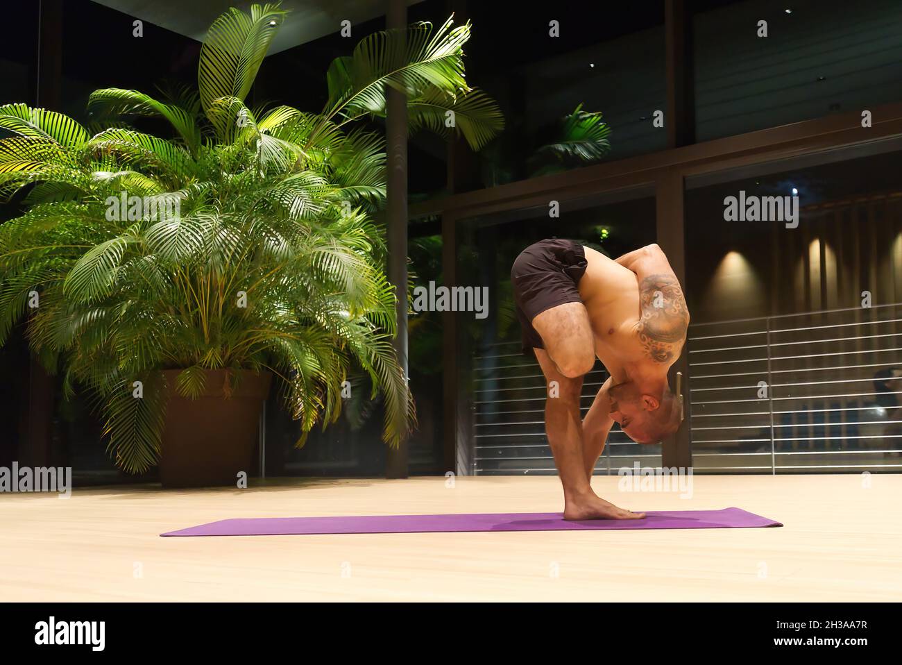 Homme caucasien âgé d'un âge moyen se positionne au yoga à l'intérieur. Banque D'Images