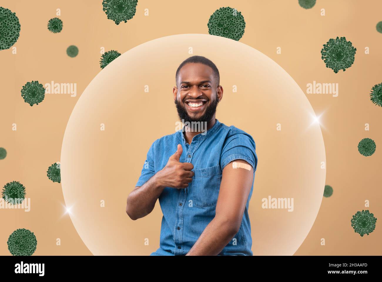 Homme millénaire noir souriant montrer l'épaule avec l'aide de bande après l'injection et le pouce vers le haut dans la protection de bulle contre le virus Banque D'Images