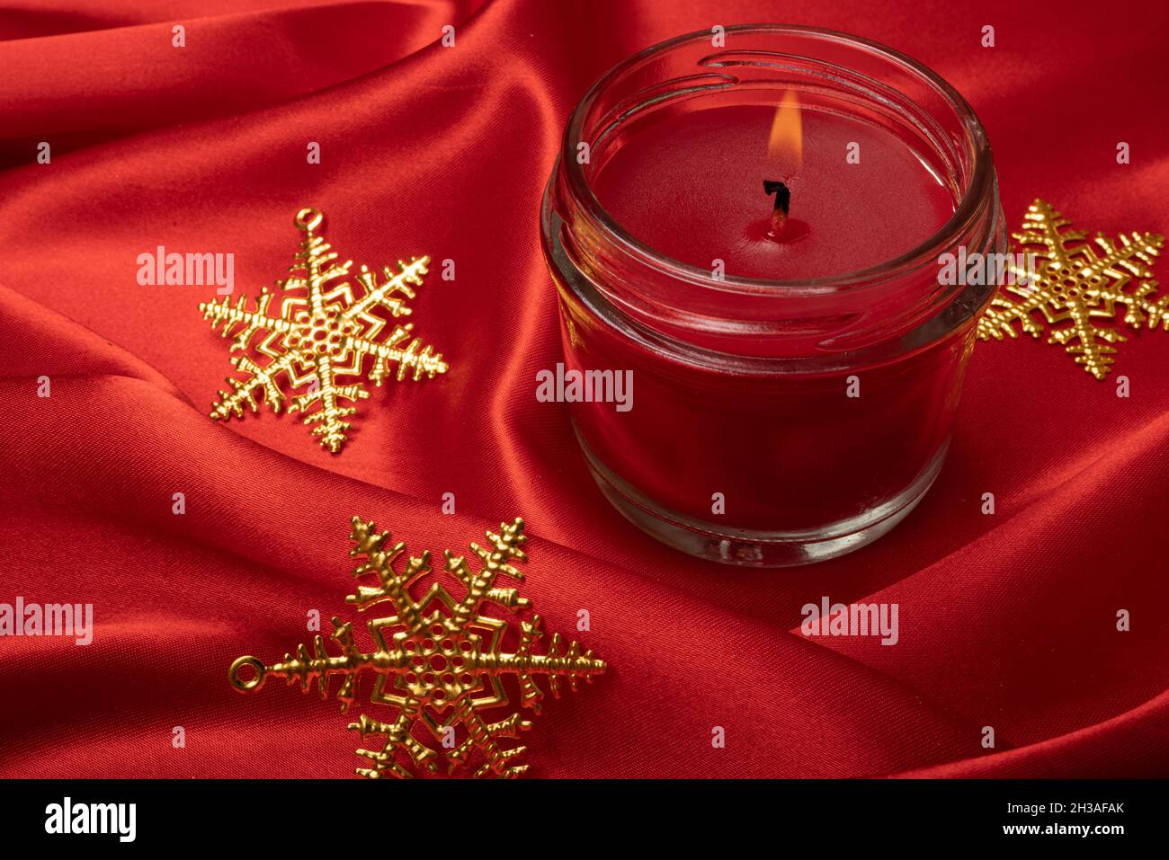Bougie parfumée rouge avec ornements étoiles de Noël sur fond de tissu en  soie rouge vif Photo Stock - Alamy