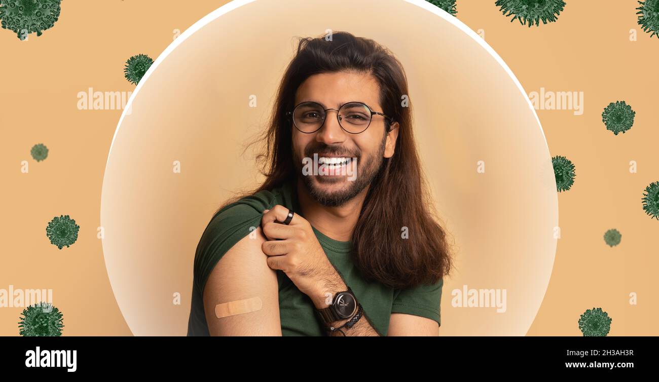 Homme millénaire arabe souriant montrant l'épaule avec l'aide de bande après la vaccination sur fond beige Banque D'Images