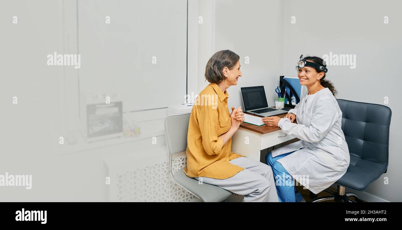 Femme mature en consultation avec un médecin ORL à la clinique médicale à l'intérieur.Traitement de la maladie d'ORL chez les personnes âgées Banque D'Images