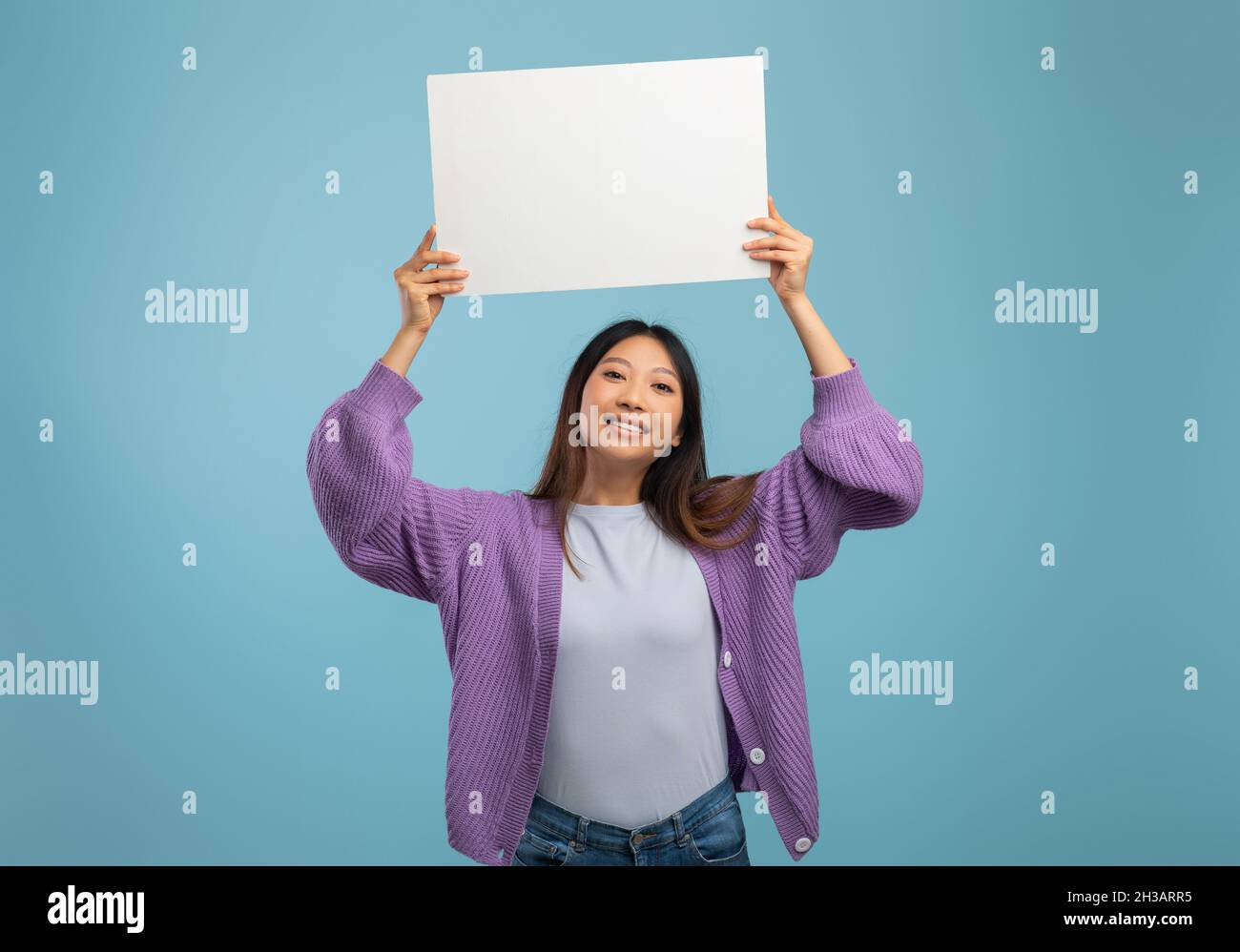 Concept de publicité.Bonne femme asiatique tenant un tableau blanc vide et souriant à l'appareil photo sur fond bleu Banque D'Images