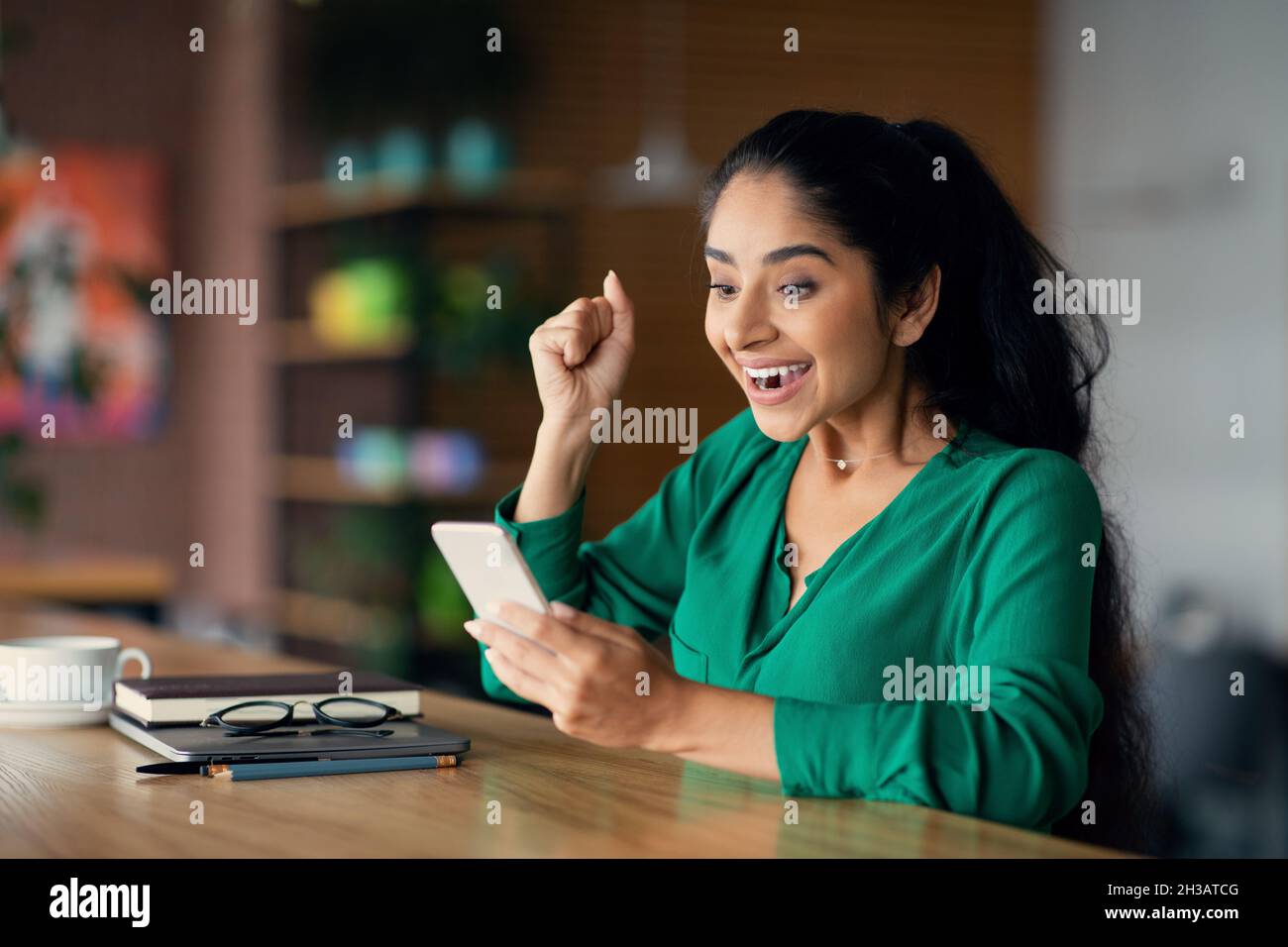 Femme du Moyen-Orient émotive ayant de bonnes nouvelles, en utilisant le téléphone cellulaire Banque D'Images