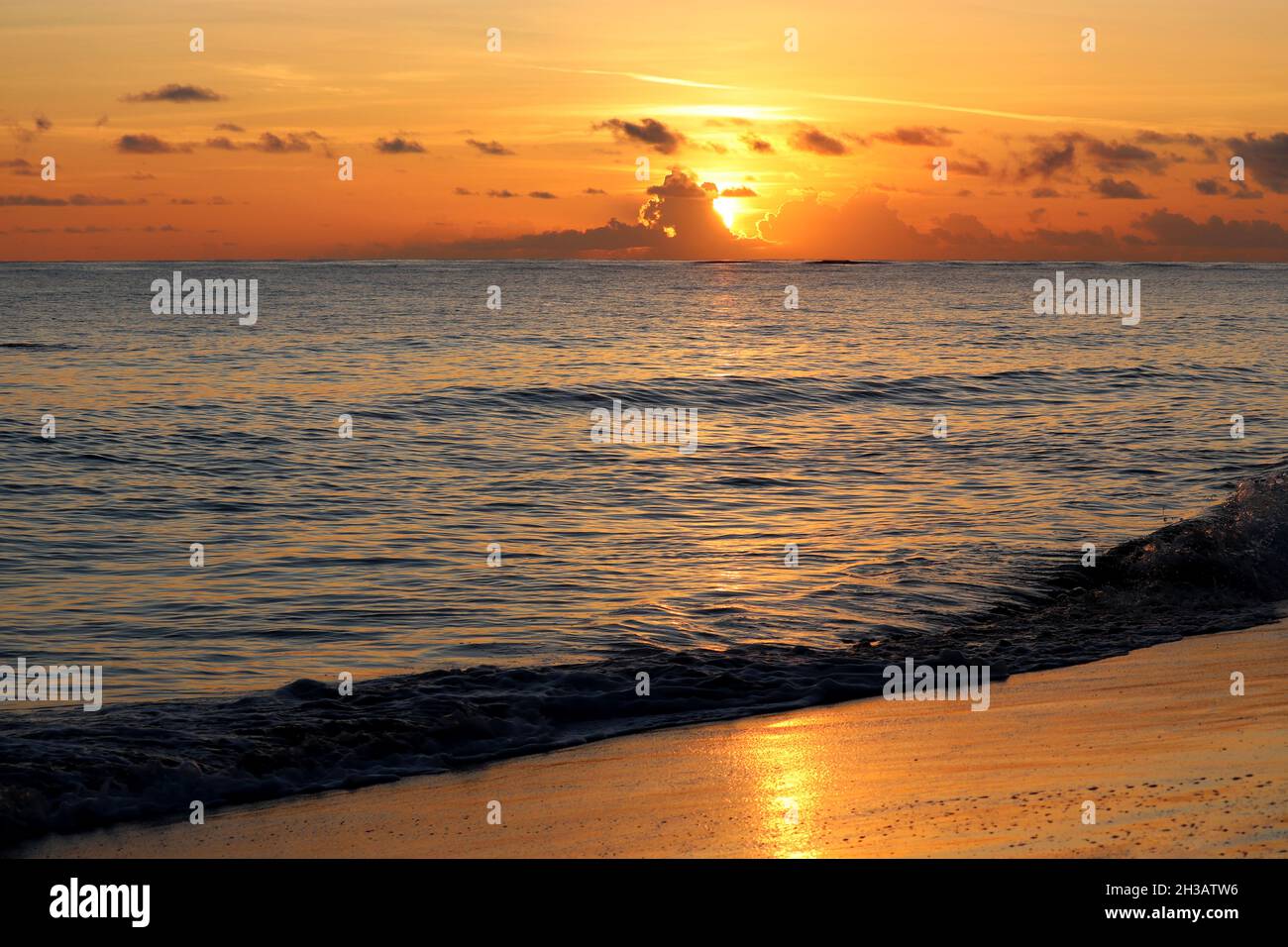 Coucher de soleil sur une plage de sable, soleil orange brille à travers les nuages.Soirée mer, fond pour un voyage romantique Banque D'Images