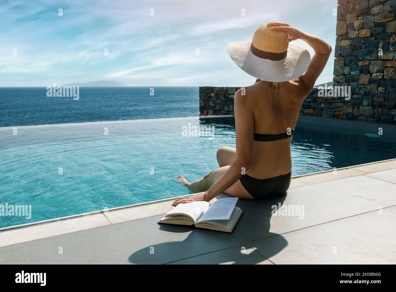 femme de bains de soleil et de détente au bord de la piscine avec vue sur la mer dans villa de luxe Banque D'Images