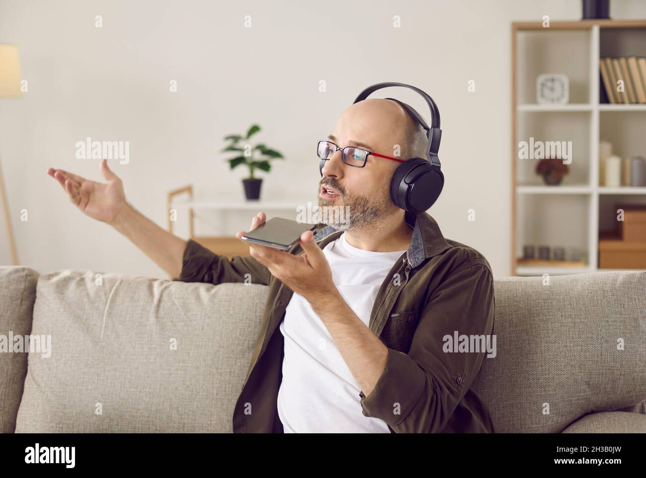 Homme dans un casque parlant sur le haut-parleur, en enregistrant un message ou en utilisant l'assistant vocal Banque D'Images