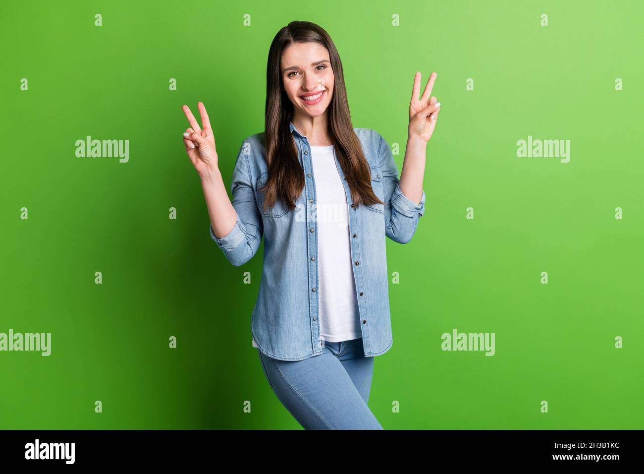 Portrait d'une fille gaie attrayante montrant le double V-signe libre temps de repos isolé sur fond vert clair de couleur Banque D'Images