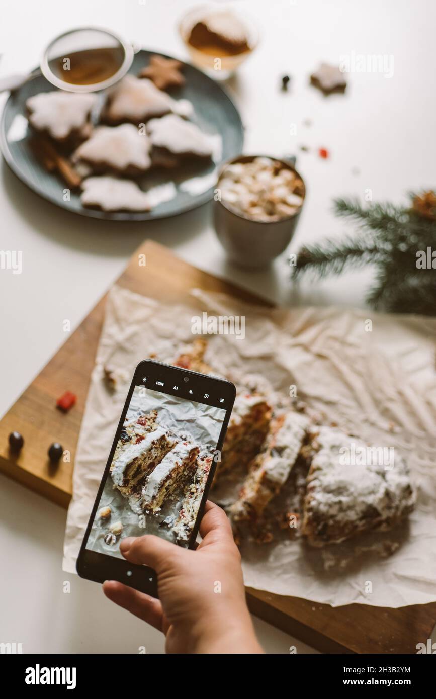 Baker prend une photo du stollen de Noël cuit au four, sur téléphone portable Banque D'Images