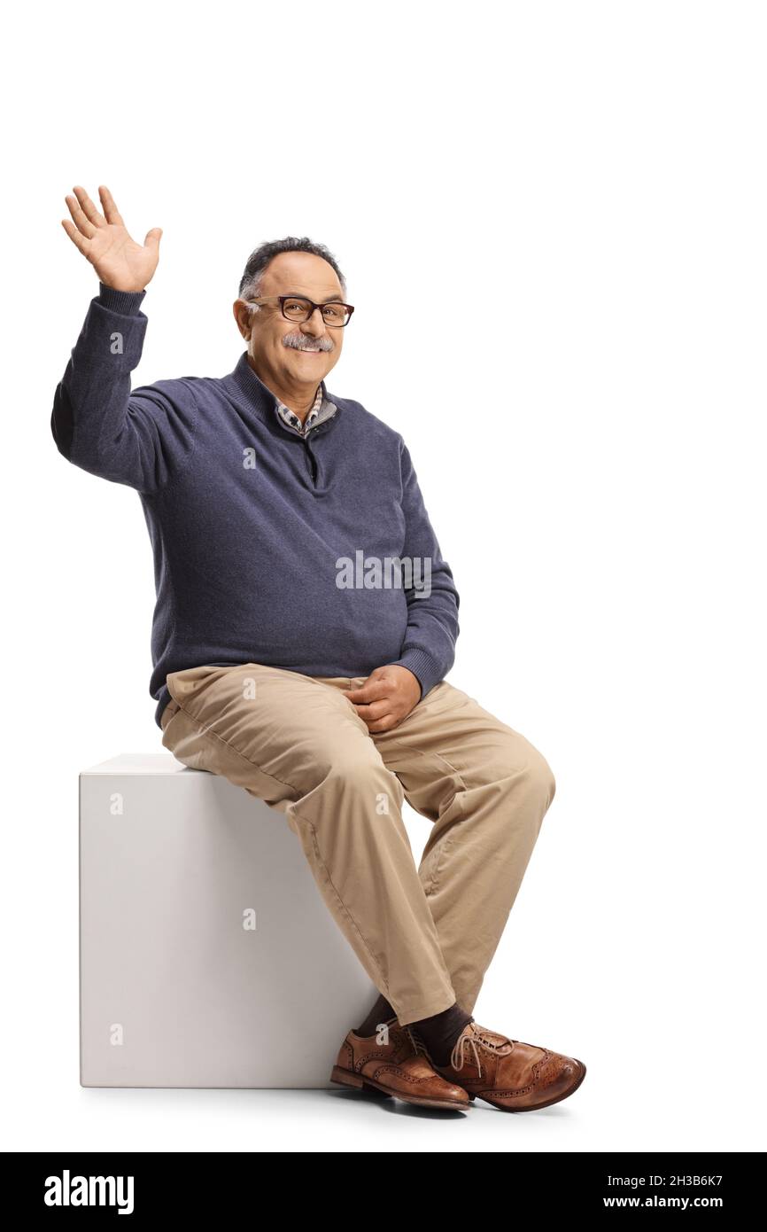 Homme adulte décontracté assis et agitant à la caméra isolée sur fond blanc Banque D'Images