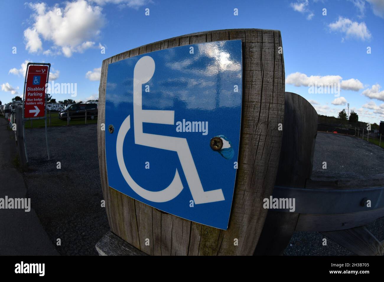 Vue en angle d'un panneau bleu pour personnes handicapées reflétant le ciel bleu montrant l'entrée de stationnement pour personnes handicapées Banque D'Images