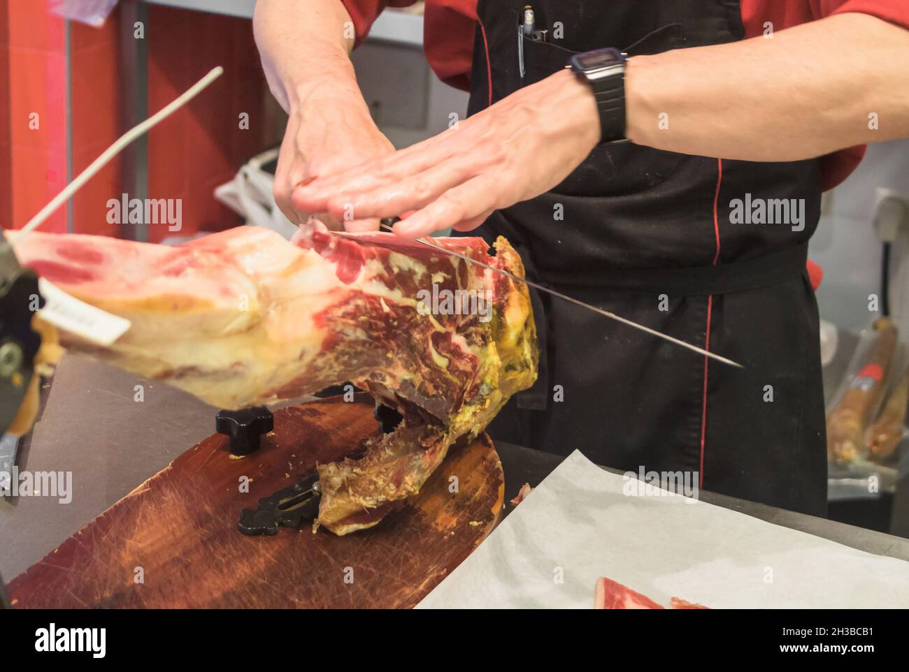 Les mains du vendeur de boucher ont coupé des morceaux de jamon sur le brouilleur Banque D'Images