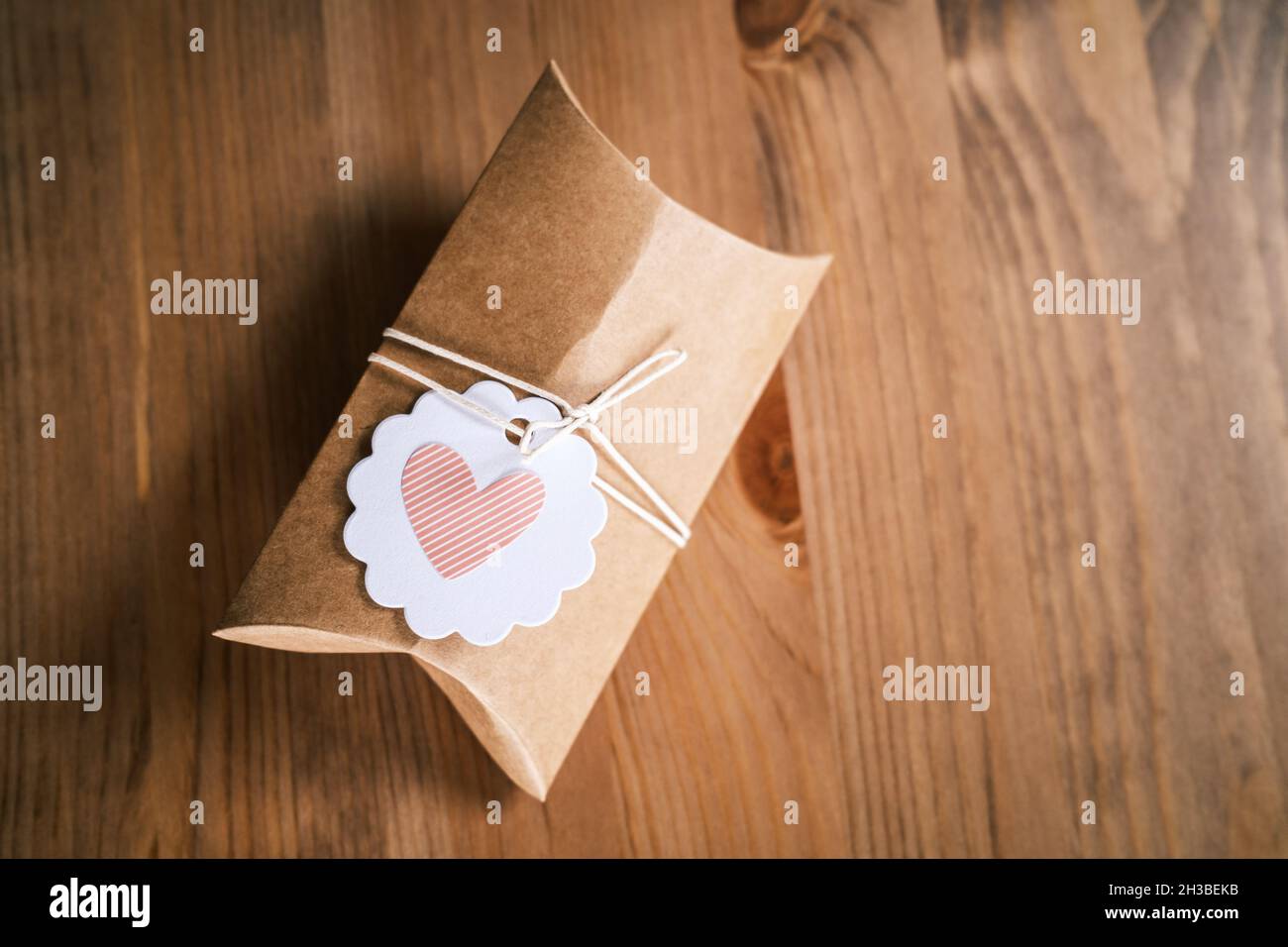 Petit cadeau enveloppé dans du papier artisanal sur fond en bois.Cadeau  fait maison, forme de coeur sur l'étiquette cadeau.Emballage de cadeaux  durable à l'aide de papier recyclé Photo Stock - Alamy