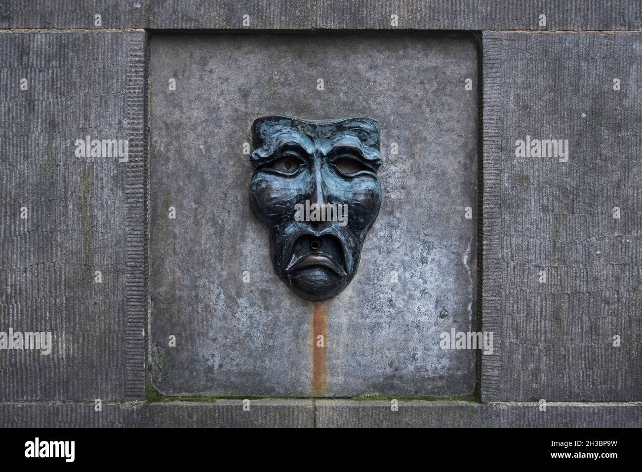 Masque de bronze avec un visage triste sur la tête de puits à l'extérieur de l'Edinburgh Fringe Office sur le Royal Mile, Edimbourg, Ecosse, Royaume-Uni. Banque D'Images