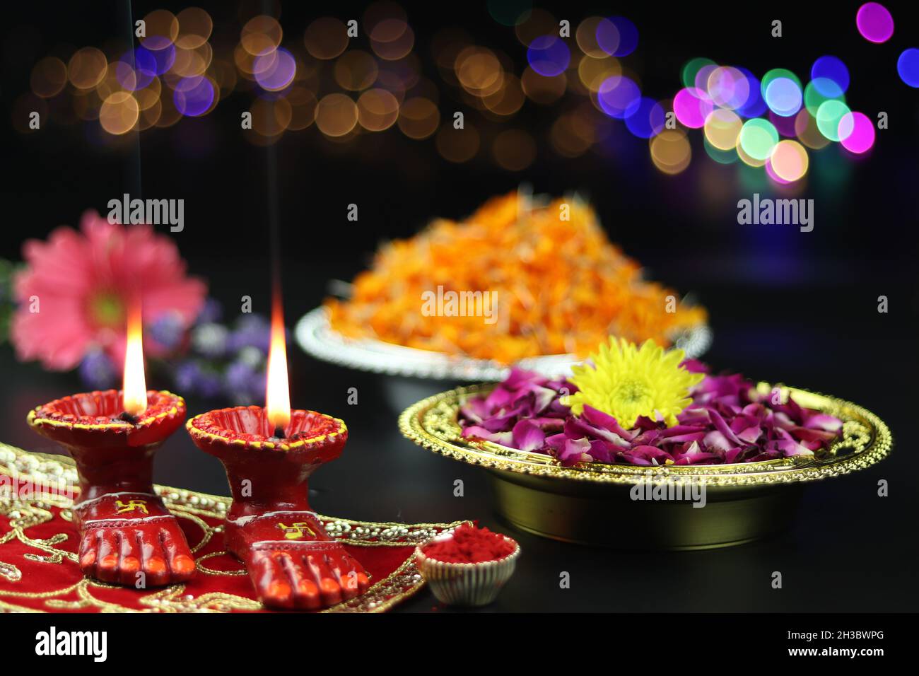 Lamp d'argile connu sous le nom de Diya, Deep, Diyo, Deepa ou Deepam avec des pieds de déesse Lakshmi Charan éclairant sur tissu rouge Asan avec des fleurs intérieures Roli et Bok Banque D'Images