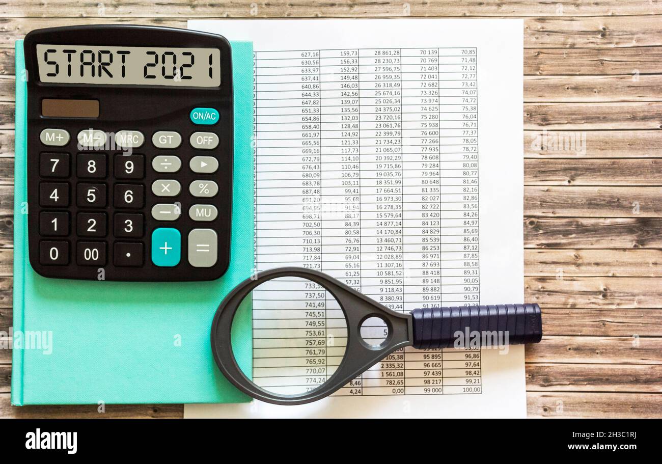 Le début 2021 est écrit sur l'écran de la calculatrice, sur le bureau avec des documents financiers et une loupe.Concept d'entreprise. Banque D'Images