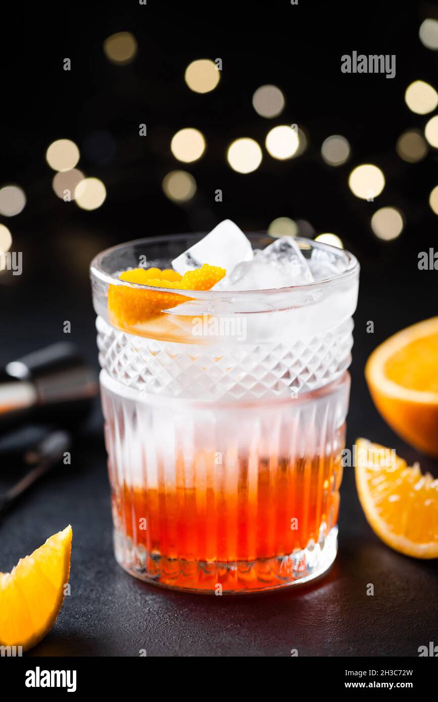 Cocktail d'alcool orange avec glace dans un verre à whisky sur fond noir.Boisson fusion créative Banque D'Images