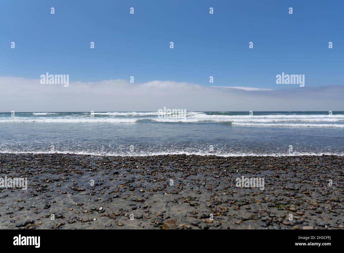 Vue floue sur les galets mouillés sur une plage avec l'océan pacifique Banque D'Images