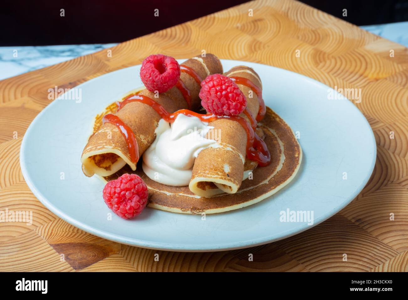 Helsinki / Finlande - 27 OCTOBRE 2021 : une assiette de crêpes norvégiennes moelleuses avec crème fouettée caramélisée et confiture de framboises sur le côté. Banque D'Images