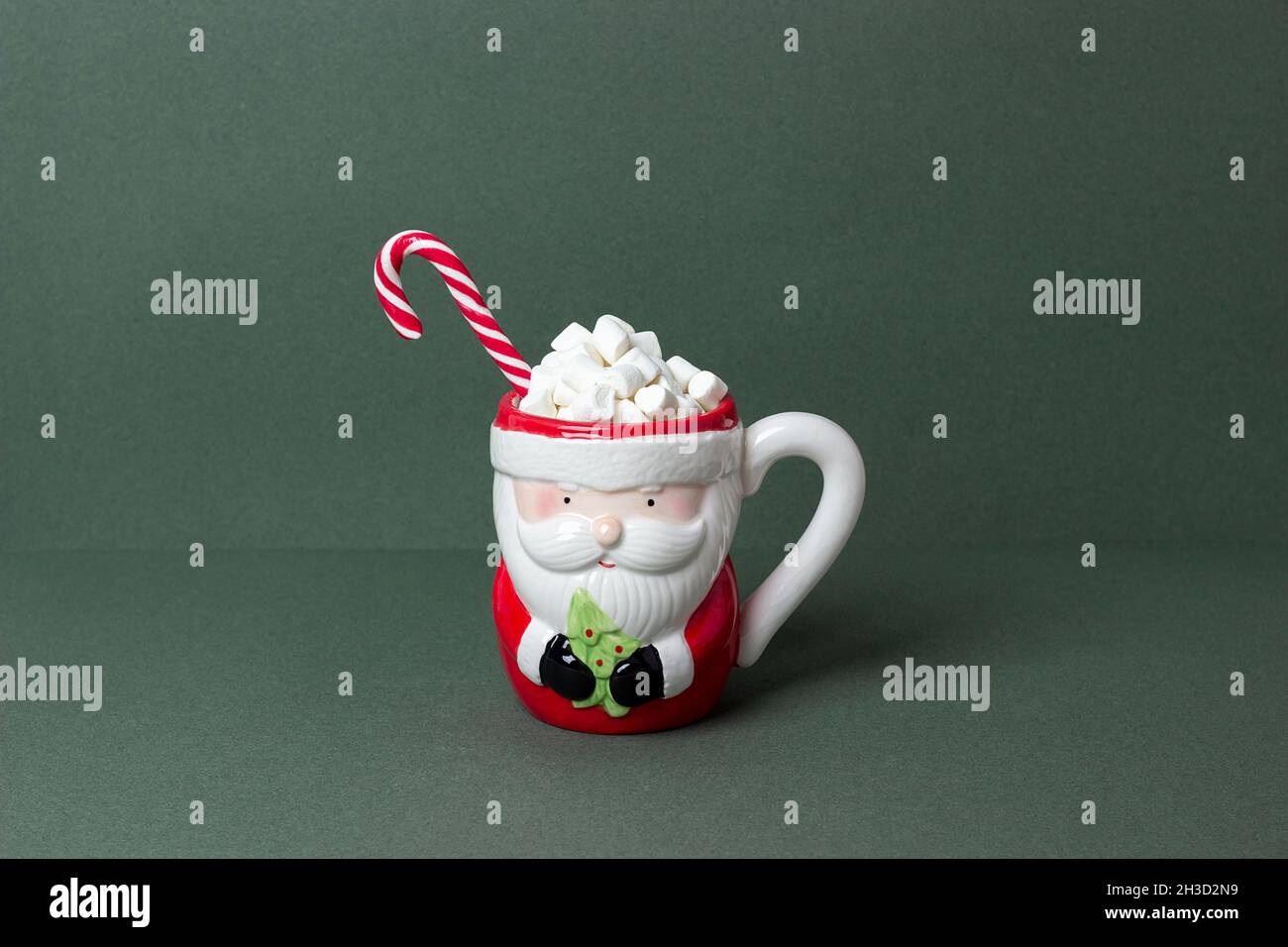 Joyeux Noël ou concept de vacances du nouvel an.Tasse de cacao amusante du père noël avec guimauves, canne à sucre sur fond vert.Style minimal Front vie Banque D'Images