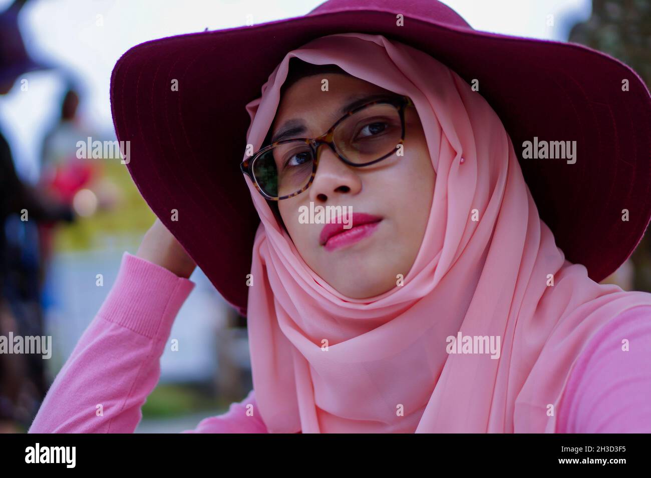 Portrait en gros plan de la belle jeune femme musulmane asiatique portant un chapeau, une robe rose et un hijab.Regarder la caméra avec l'expression du visage de poker. Banque D'Images