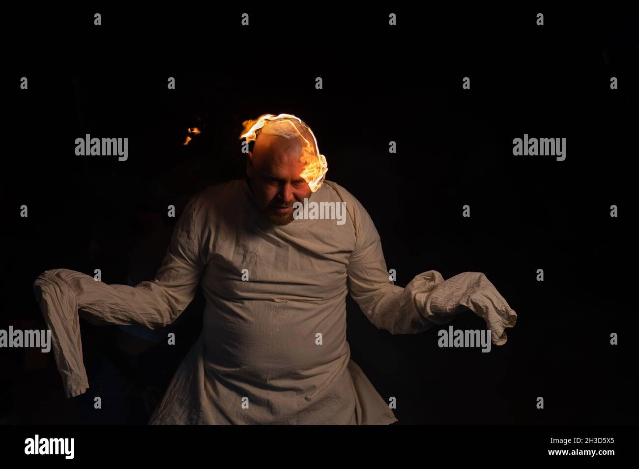 Homme chauve dans un blouson avec une tête brûlante sur un fond sombre. Banque D'Images