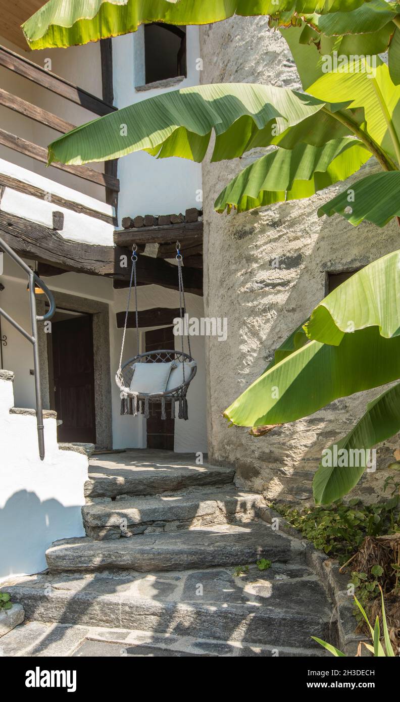 Belle chaise ronde ou fauteuil suspendu à l'entrée d'une maison suisse.Idéal pour passer des vacances.Jour d'été ensoleillé. Banque D'Images