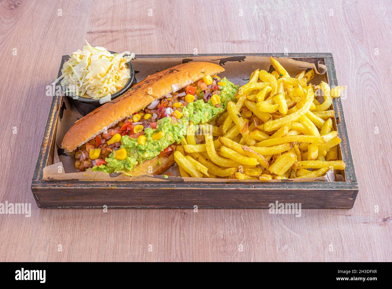 Hot dog mexicain avec guacamole, maïs doux, pico de gallo et fromage avec coleslaw et frites Banque D'Images