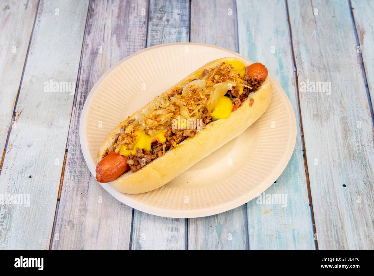 Hot dog garni de piment de bœuf épicé avec oignon et fromage cheddar fondu Banque D'Images