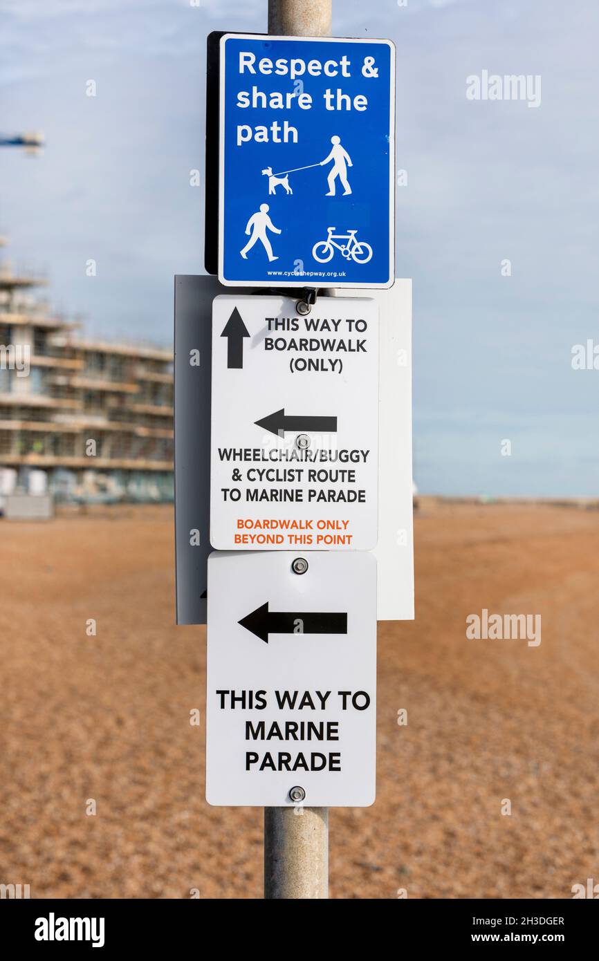 Plusieurs panneaux de direction et d'instruction sur un poteau sur une plage de galets. Banque D'Images