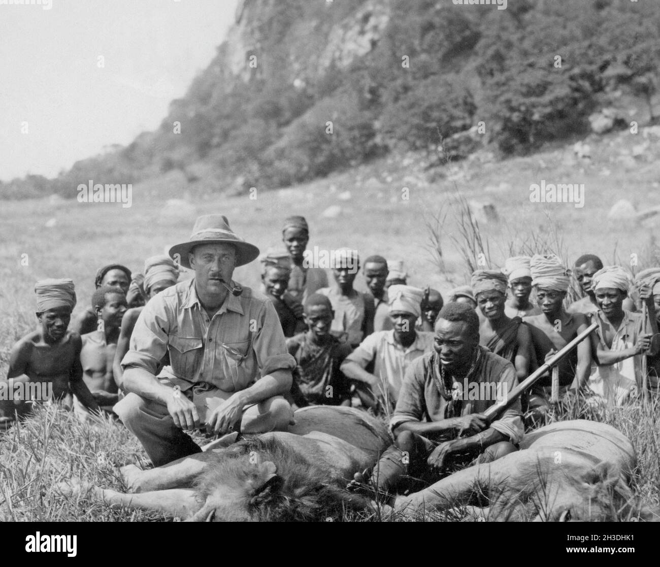 Hunter dans les années 1930.Un homme blanc ayant tiré deux lions est vu avec les animaux morts et les autochtones regardant sur.Afrique années 1930 Banque D'Images
