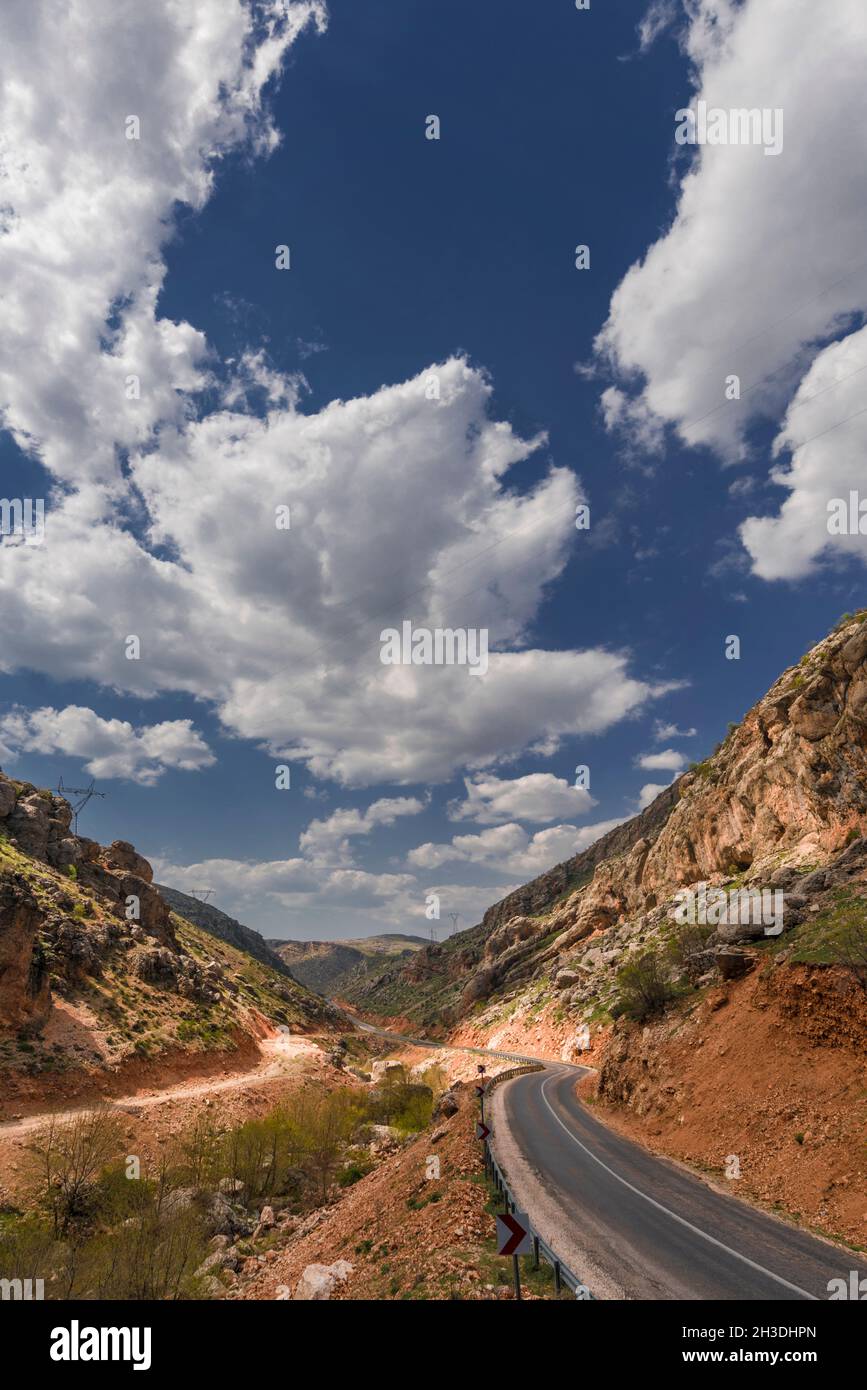 route de montagne pénétrant dans une gorge lors d'une journée ensoleillée avec des nuages et des clairières Banque D'Images