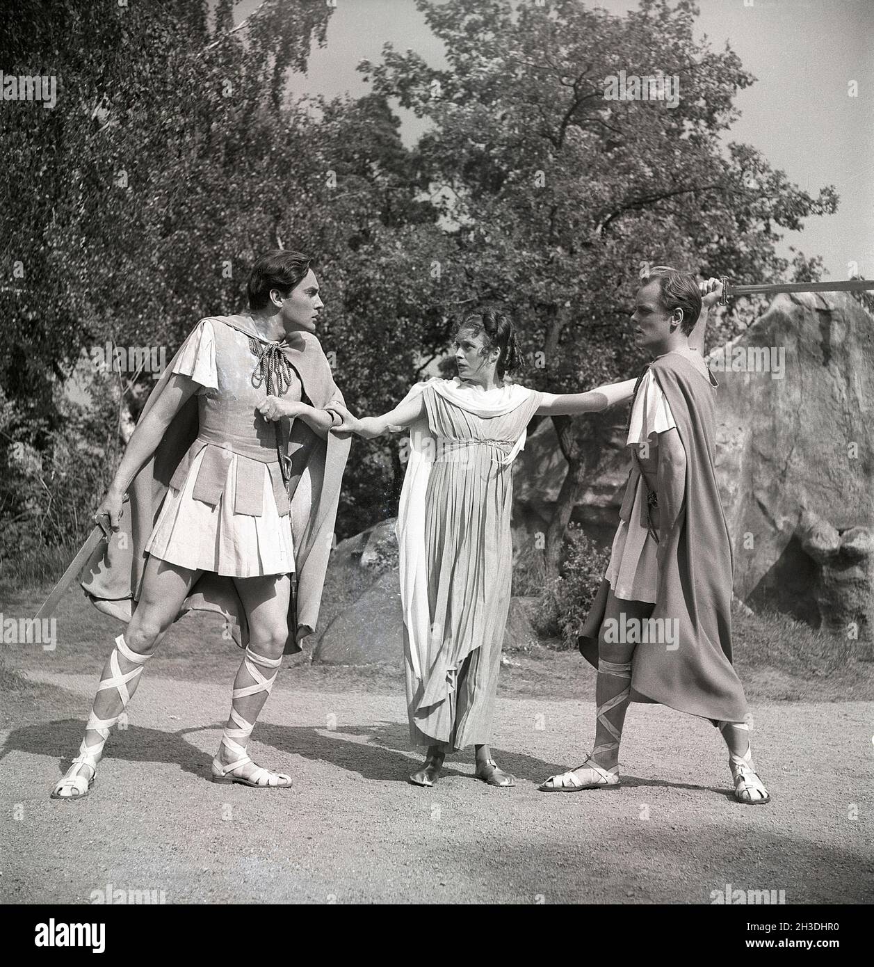 Dans le théâtre dans les années 1940.Un théâtre en plein air de la pièce Un rêve de la nuit du milieu de l'été écrit par William Shakespeare.Une femme se tient entre deux hommes qui se regarde avec colère les uns les autres en tenant des épées.Suède 1946. Réf. U47-5 Banque D'Images