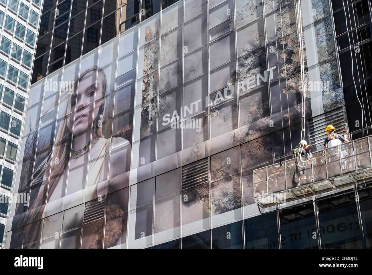 Hong Kong, Chine.06e octobre 2021.Les travailleurs installent une affiche publicitaire commerciale en hauteur de grande taille de la marque française de luxe Yves Saint Laurent (YSL) sur une façade de bâtiment à Hong Kong.(Photo de Budrul Chukrut/SOPA Images/Sipa USA) crédit: SIPA USA/Alay Live News Banque D'Images