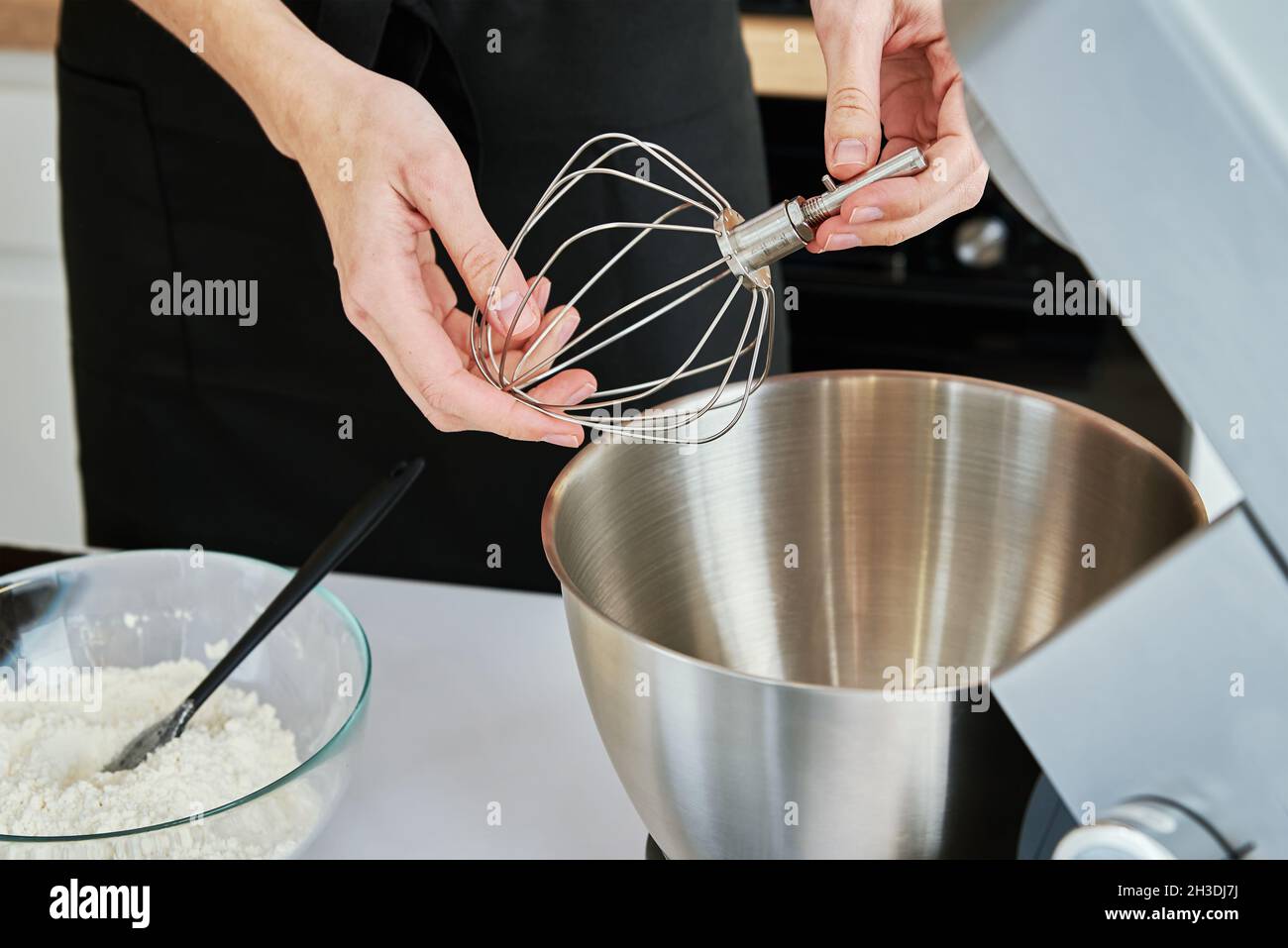 Femme mise dans un batteur électrique avec une brosse pour fouet.Appareils de cuisine Banque D'Images