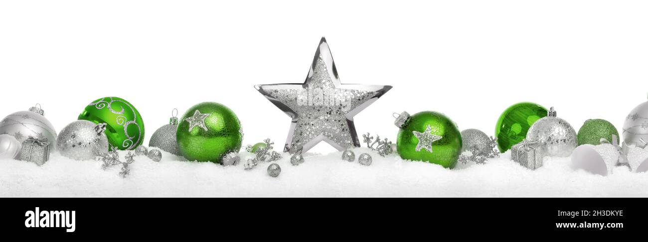 Décoration de Noël avec des étoiles et des boules en argent et vert disposées en rangée sur neige, isolée sur fond blanc Banque D'Images