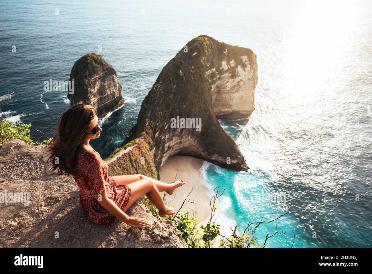 Belle fille assise sur un haut rocher et regardant la mer.La fille est assise sur le bord de la falaise.La fille de la mer.Paysage marin.Fille au coucher du soleil.Excursion en mer. Banque D'Images