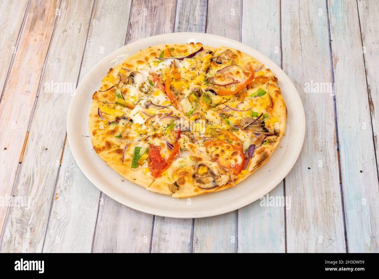 Pizza aux légumes avec fromage de pomme de terre, maïs doux, oignon rouge, tomate émiettée, oignon rouge,tranches de champignons et d'origan Banque D'Images