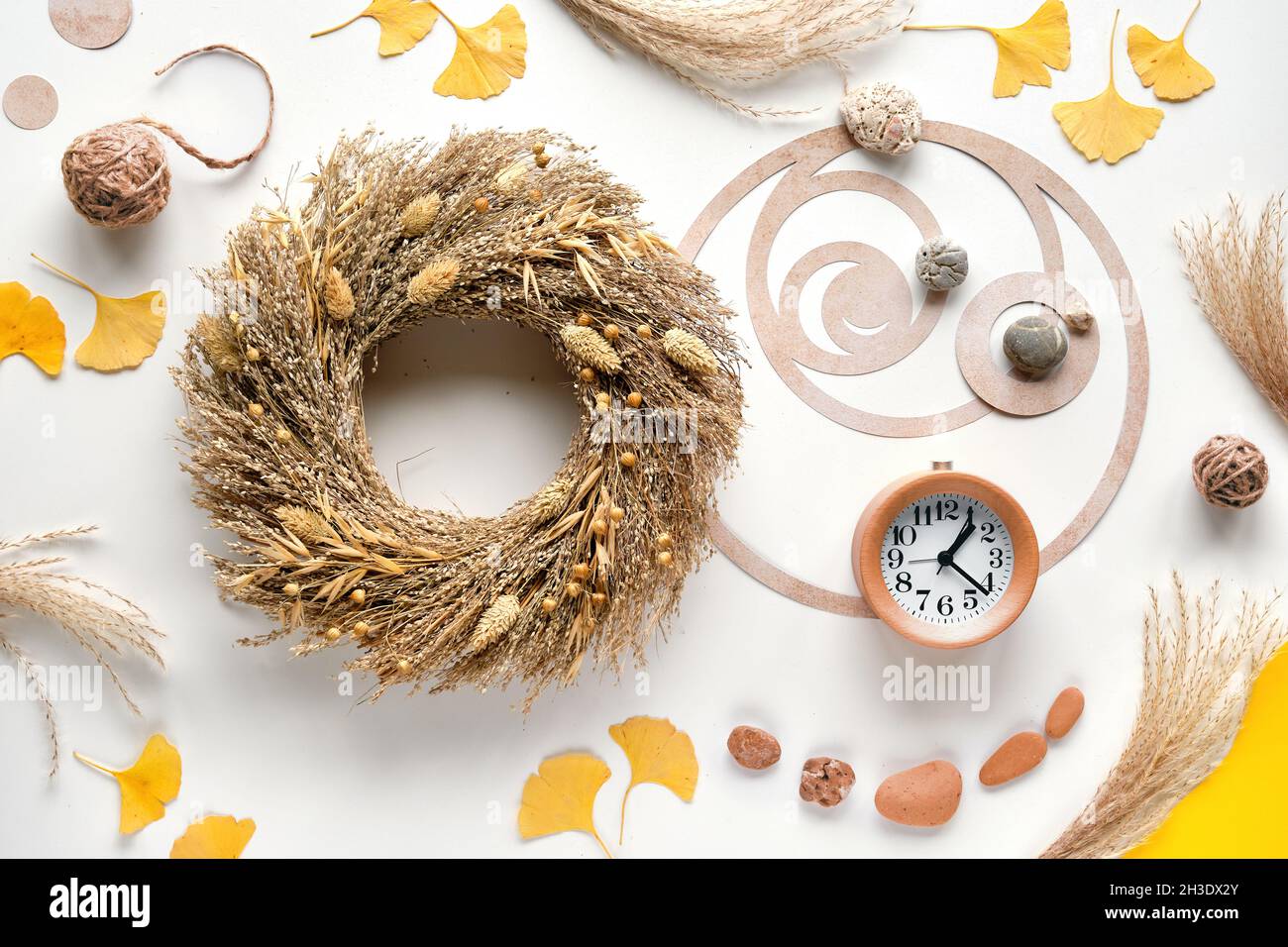 Réveil en bois, couronne sèche, table blanche avec feuilles de ginko, pierres et pampas.Cercle de séquence Fibonacci.Golden ratio concept automne Banque D'Images