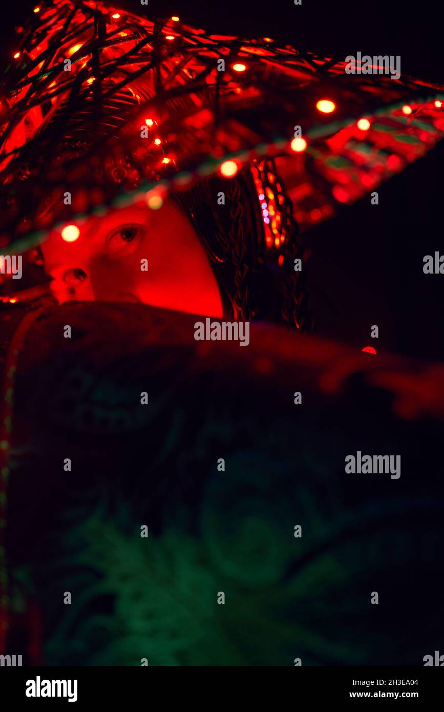 Femme énigmatique dans une tenue traditionnelle créative et coiffeuse vietnamienne avec éclairage rouge dans un studio sombre sur fond noir pendant la perfo Banque D'Images
