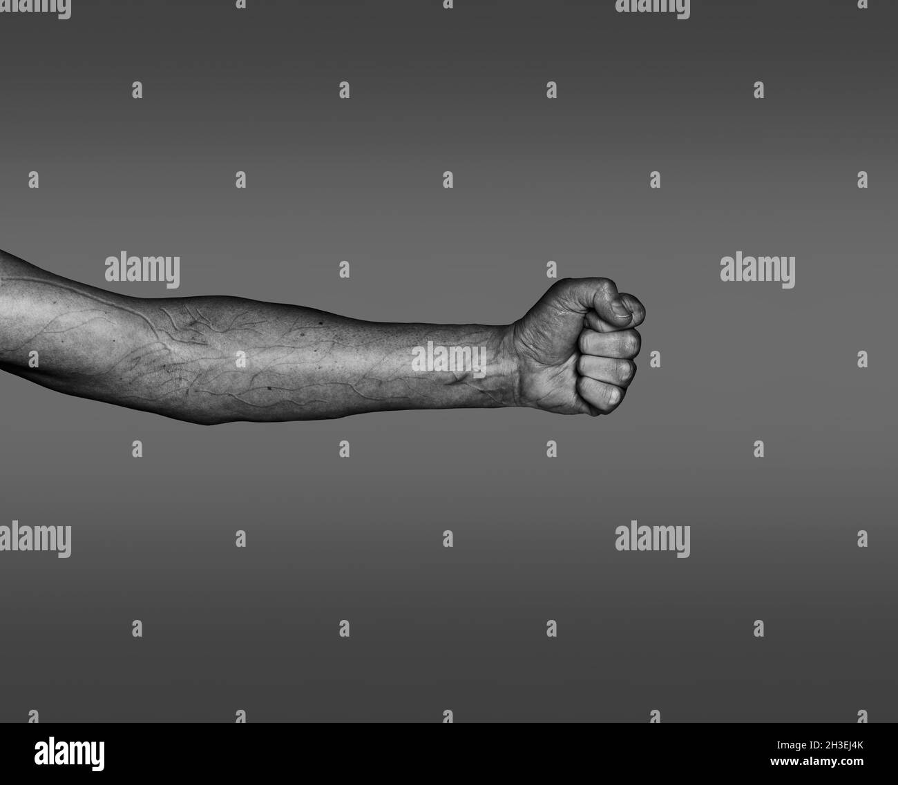 Image en noir et blanc du bras de l'homme à la peau claire avec le poing trempé et les veines saillantes Banque D'Images